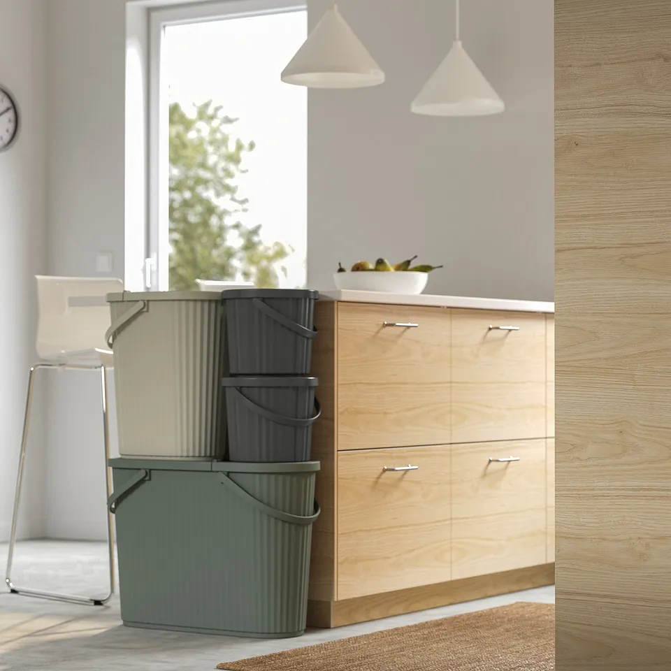 Modern kitchen with stacked DAMMÄNG bins, featuring a lid, foldable handle, and space-saving design near wooden cabinets.