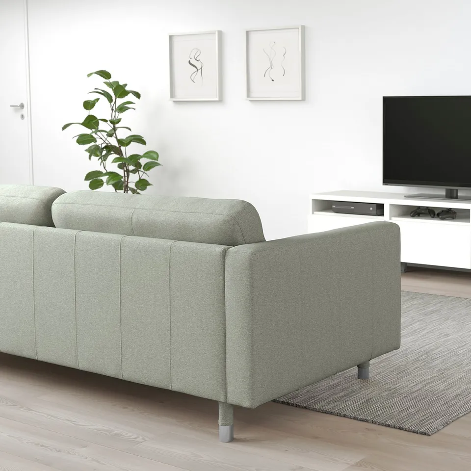 Modern green LANDSKRONA sofa against white wall, small plant, tv in background.