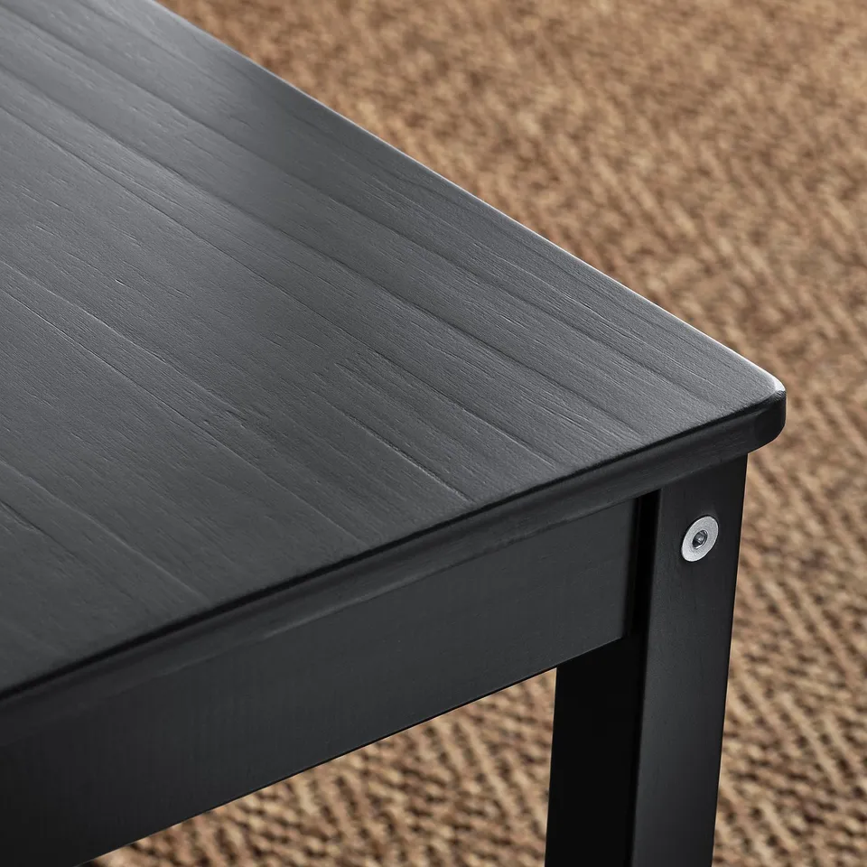 Close-up of dark wood table edge, showcasing smooth finish and sturdy construction.