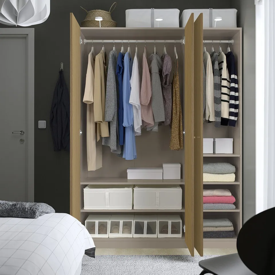 Open wardrobe with clothes, folded items, and storage bins, showing organised bedroom storage solution.