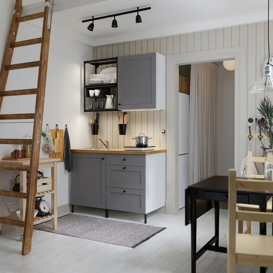 Modern kitchen with grey SKURUP lamps over counter, wooden ladder, and dining area.