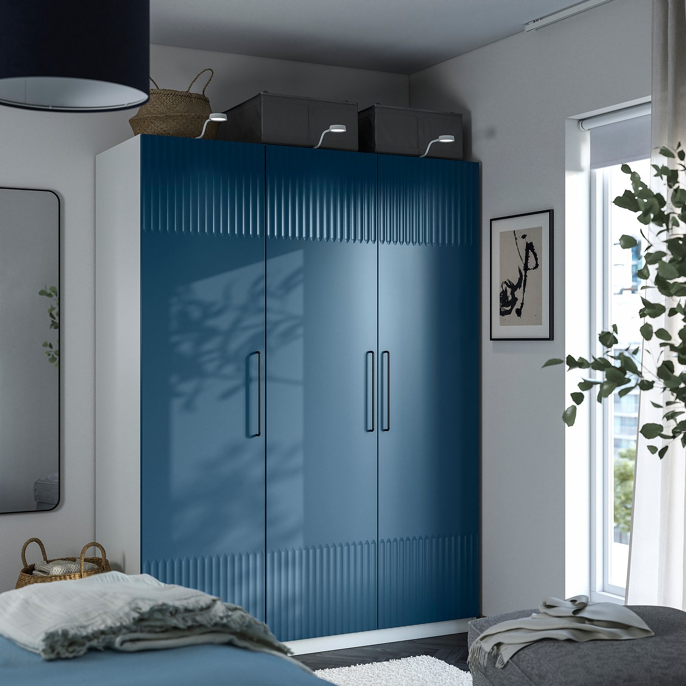 Modern bedroom with tall blue PAX wardrobe, silver handles, natural light, plant, light bed linens