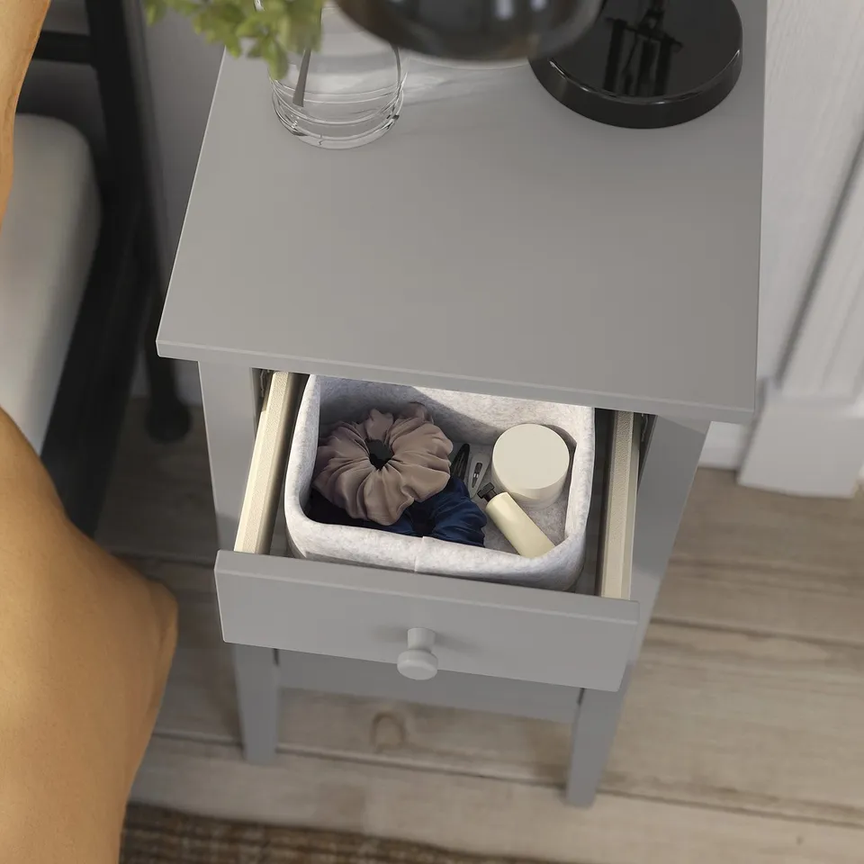 Small light grey bedside table with drawer, containing a felt organiser with accessories.