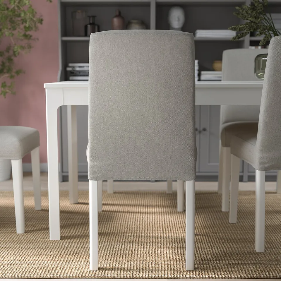 Three modern grey fabric dining chairs with white legs around a white extendable table, cosy setting with rug and decor.