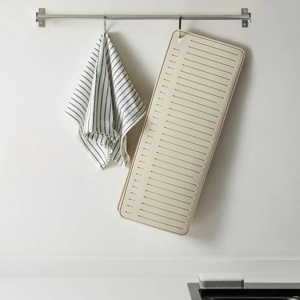 A kitchen drying mat hangs on a wall hook for air circulation and neatness.