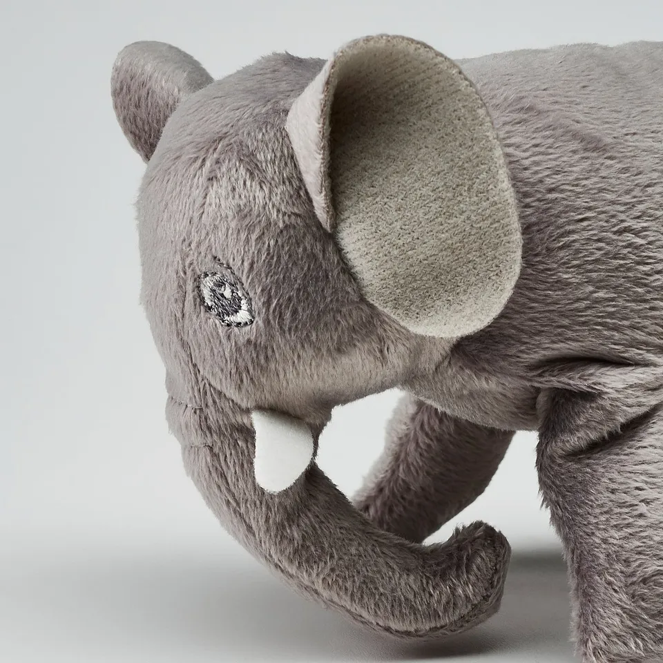 Stuffed grey elephant toy, soft, plush, with white tusks, detailed black eye, eco-friendly.