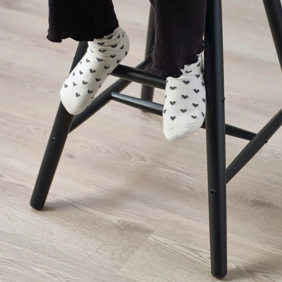 Child sitting on a junior chair, legs dangling, wearing socks with heart patterns.