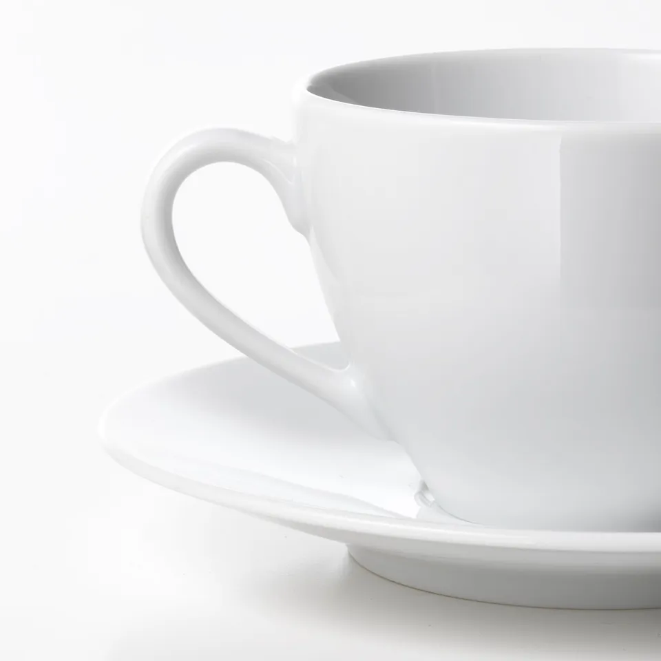 Clean white porcelain cup on saucer. Rounded handles, smooth finish. High-quality tableware set.