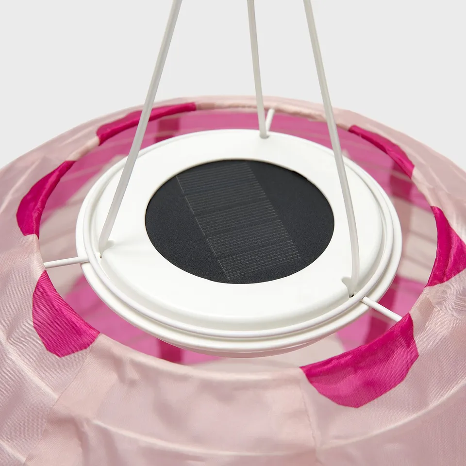 Solar-powered hanging lamp with pink fabric strips, white frame, and central solar panel.