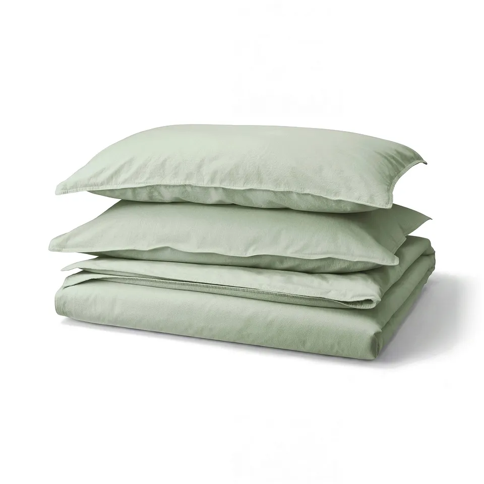 Light green bed linen set with folded duvet cover and pillows, soft cotton texture.