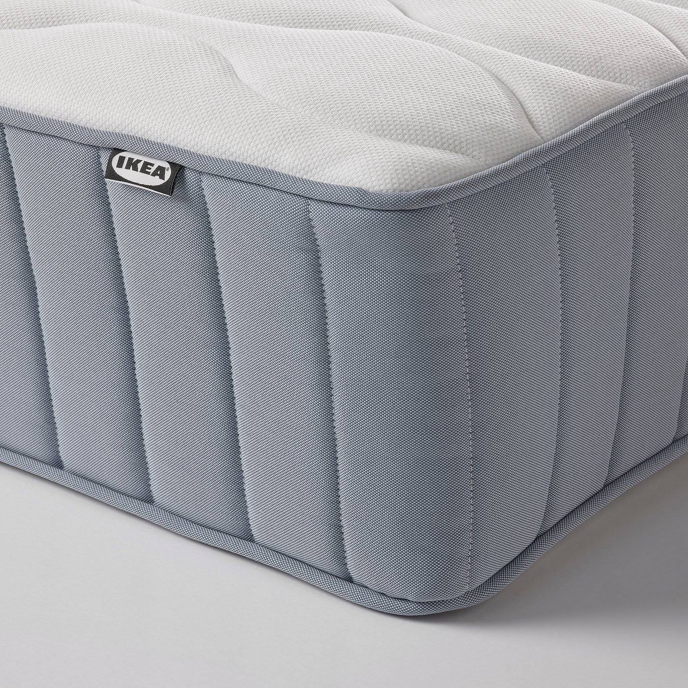 Close-up of a firm, VÅGSTRANDA mattress by IKEA. A quilted top, and vertical stitching for reinforced support.