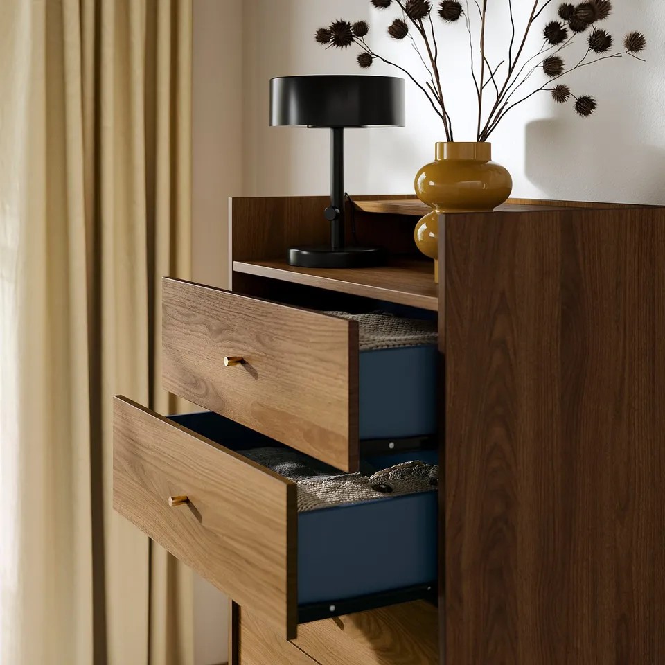 Mid-century chest of drawers with five wooden drawers, brass knobs, black legs, blue interior, and a black lamp on top.