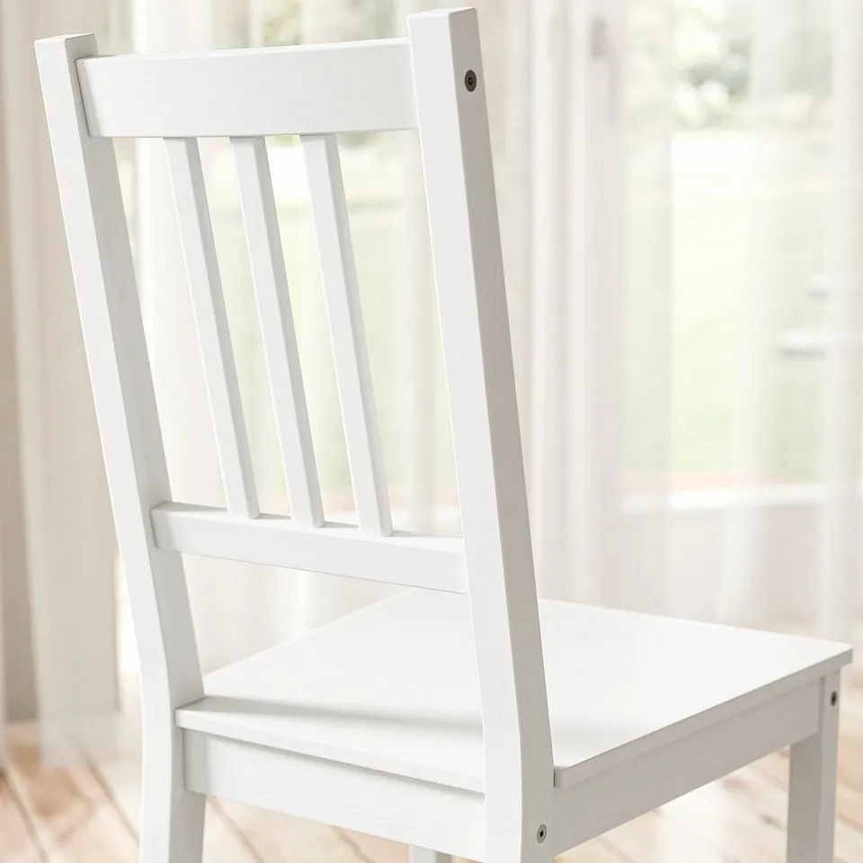 White wooden chair near bright window.