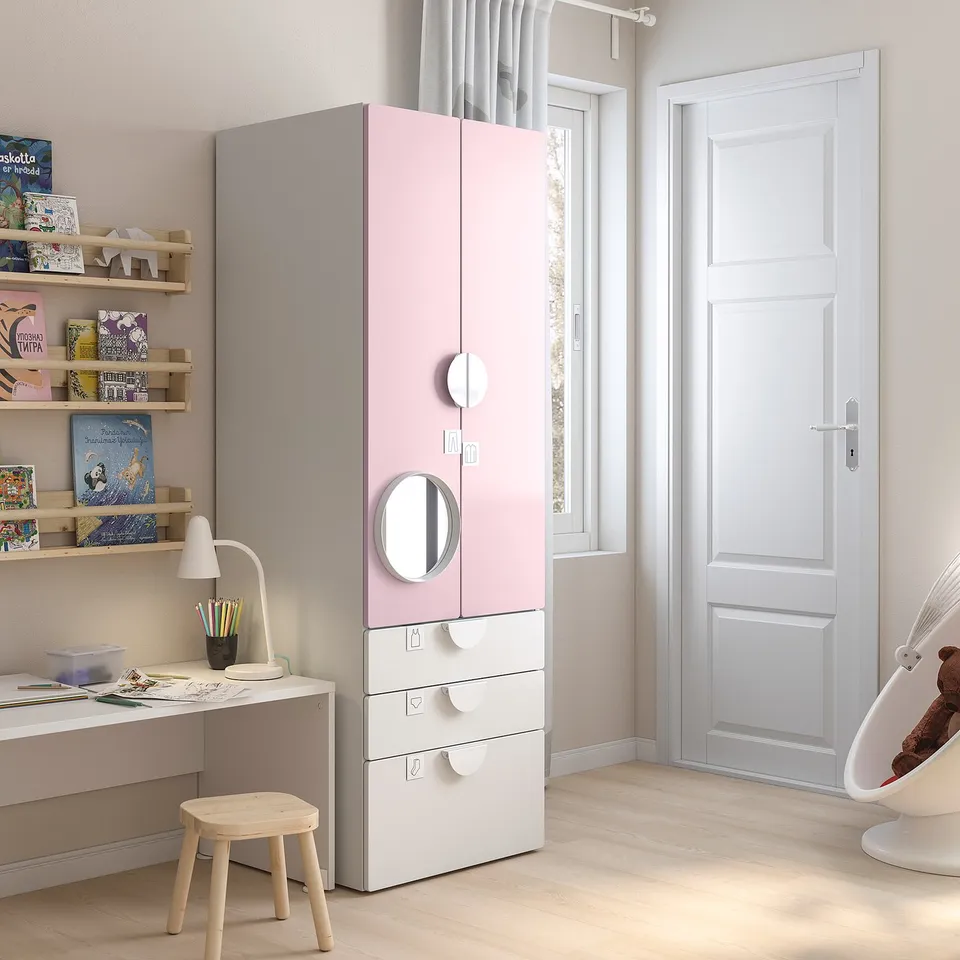 Pink and white kids wardrobe with mirror, drawers, and shelves. Modern design, light wooden floor.