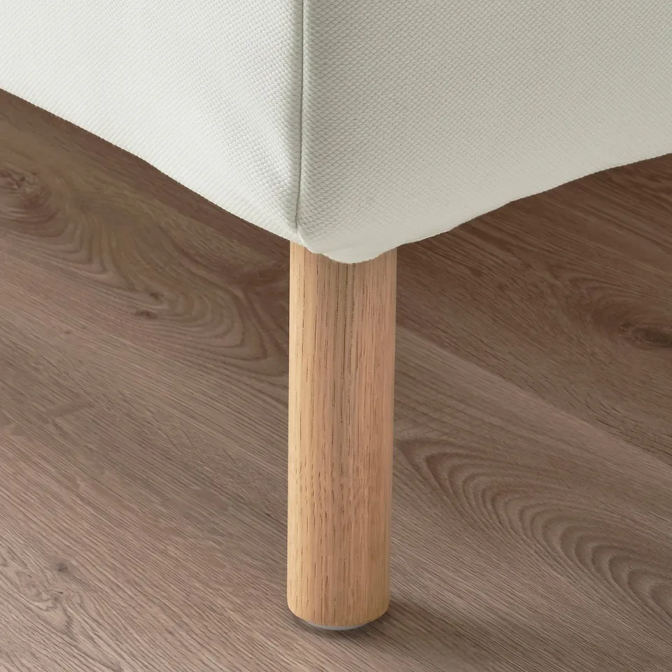 A modern bed with a white headboard and wooden legs, showcasing quality design.