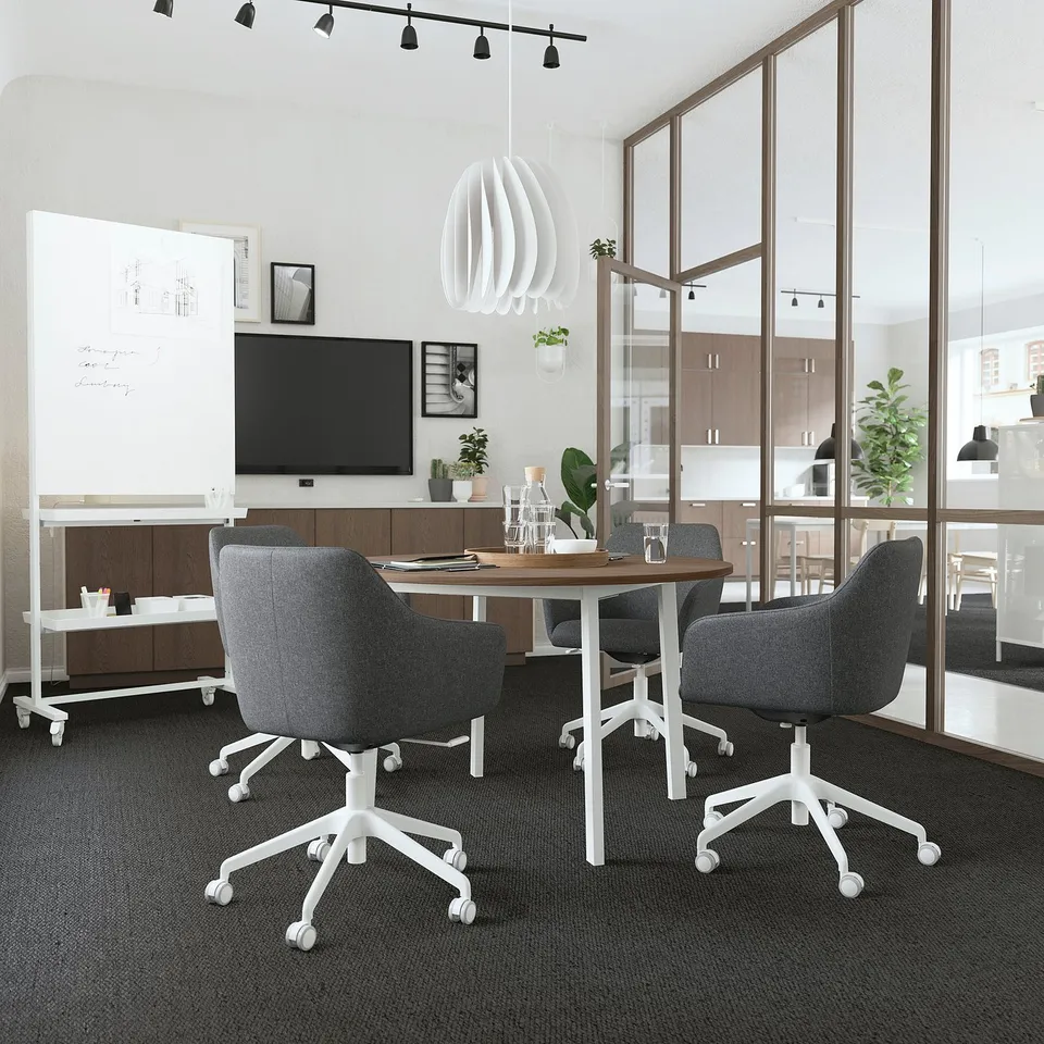 Modern office with MITTZONs round, wooden table and grey chairs. White underframe. Well-lit, sleek design. Small for intimate meetings.