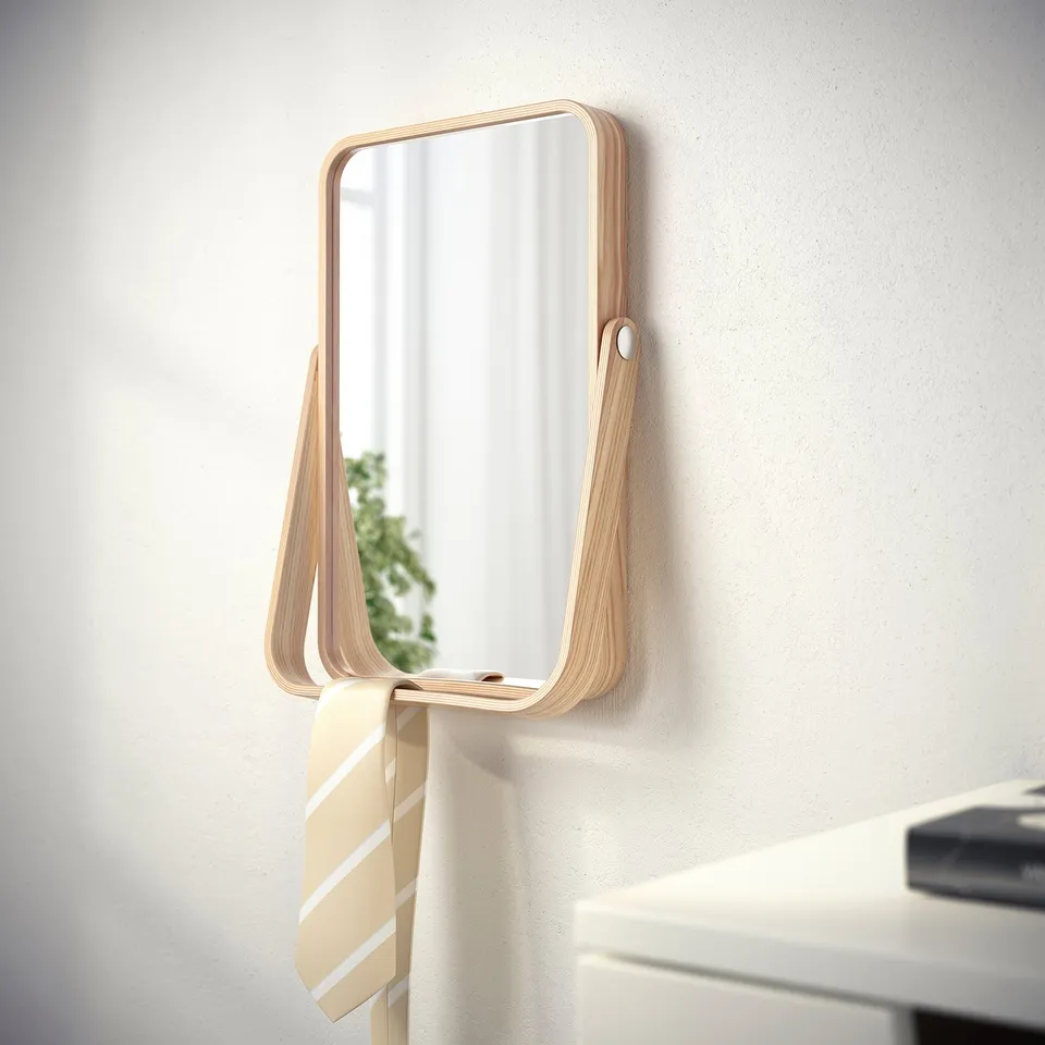 A wall-mounted mirror with a wooden frame and a shelf for holding scarves or ties, safely attached to the wall.