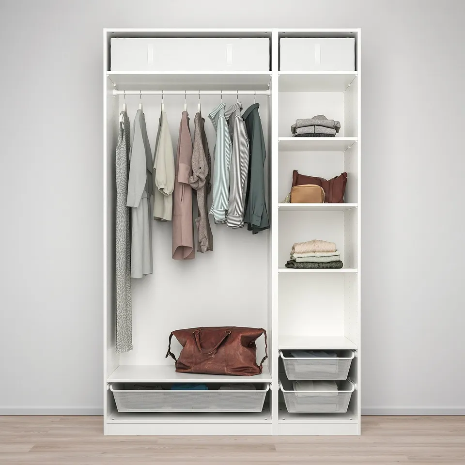 A white PAX wardrobe with clothes hangers, folded clothes, and storage bins. The top shelf has covers and the bottom shelf holds a leather bag.