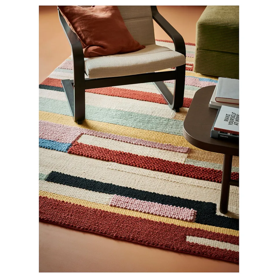 Vibrant, multicoloured striped rug with various textures in a cosy living space.