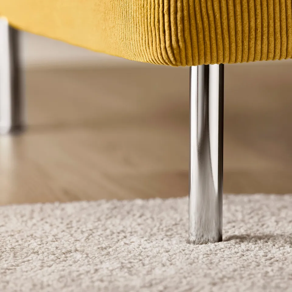Close-up of yellow SÖDERHAMN sofa leg on textured rug.