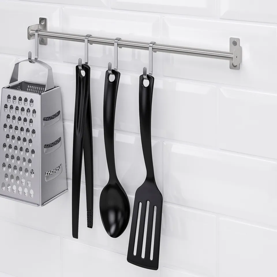 Kitchen tools hang from a wall-mounted rail, saving workspace. A grater and ladle are among the items displayed.