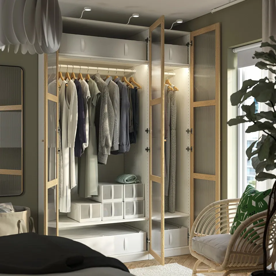 A modern open wardrobe, PAX, with clothes, storage boxes, and lighting.
