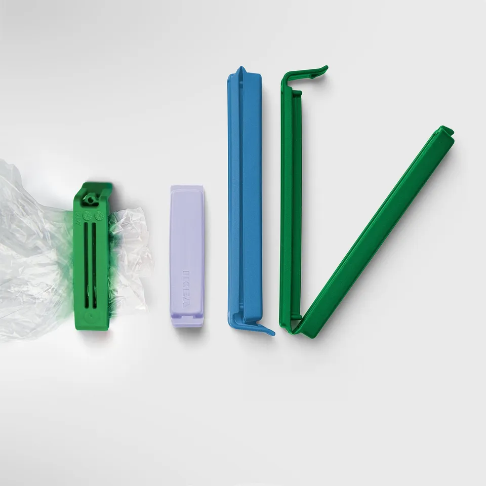 Four colourful bag sealing clips in green, purple, blue, and green, displayed in pairs with one showing a seal in use.