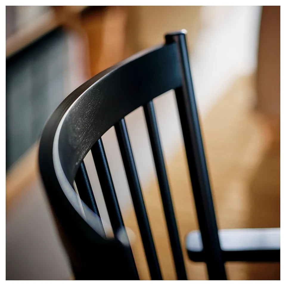 Black metal chair back with sleek, curved lines. Durable, seamless welds. Modern, minimalist design.