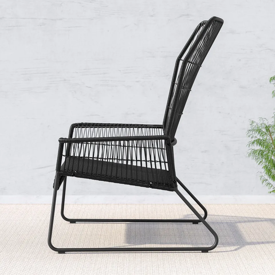 Black wicker outdoor chair with curved metal legs, designed for comfort and easy cleaning, placed on a tiled patio.