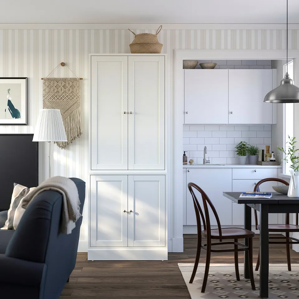 Modern kitchen with white HAVSTA cabinets, dark blue and brown furnishings, wood floor, hanging lamp, and macrame wall art.
