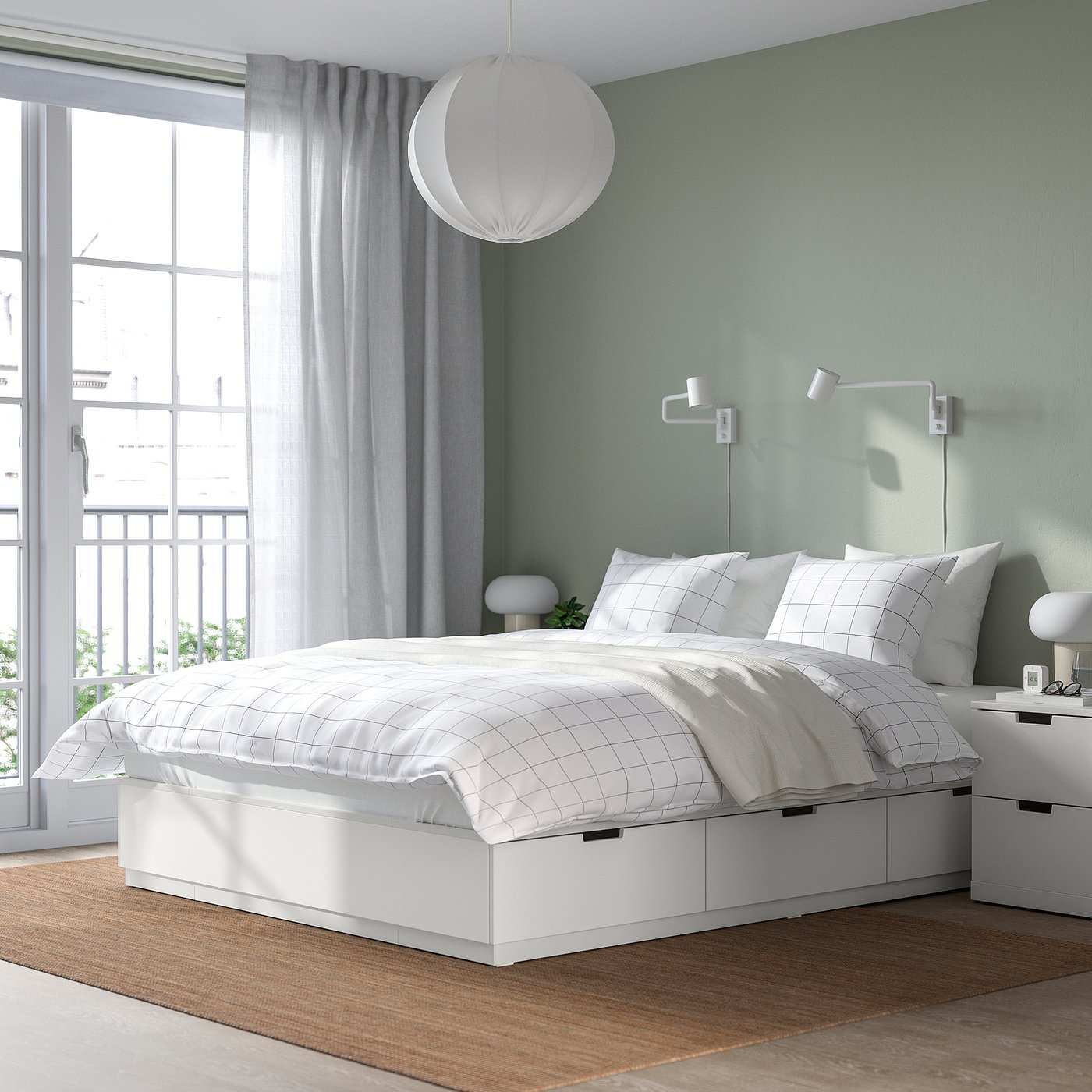 White bed in bright bedroom with round light and large window.