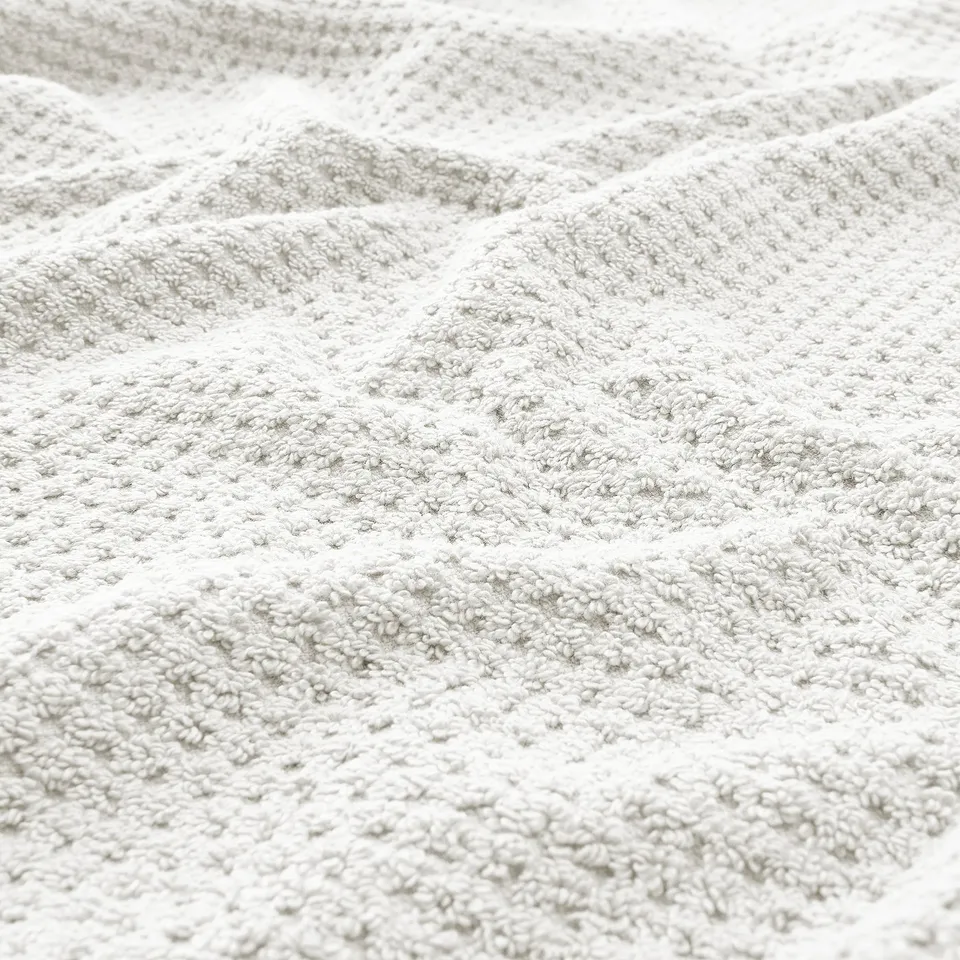 Close-up of soft, beige GULVIAL towel showcasing its thick, fluffy texture and intricate weave.
