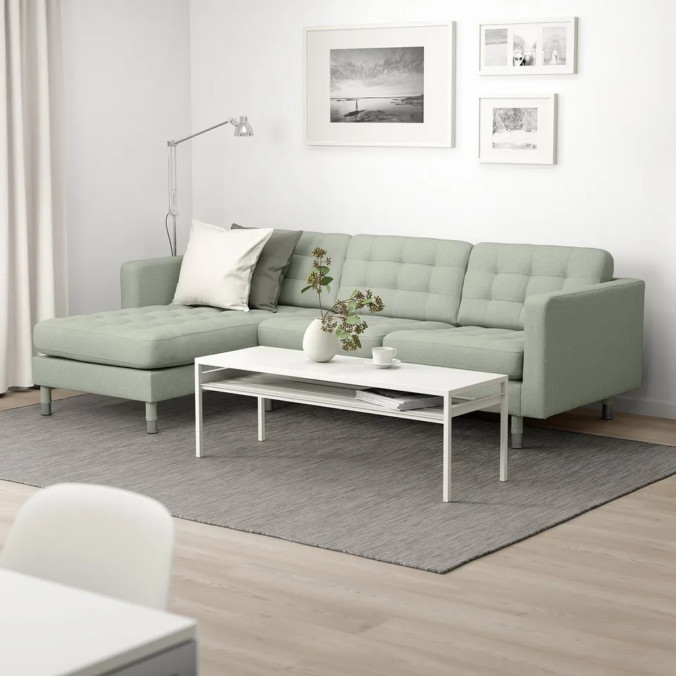 Modern living room: green LANDSKRONA sofa with 2 cushions, white coffee table, grey rug, black & white artwork.