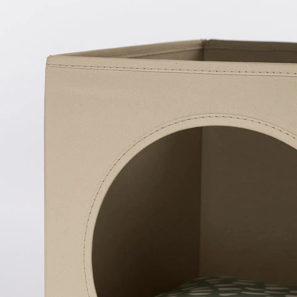 Close-up of sturdy, beige cat house corner with neat stitching, folded flat for storage.