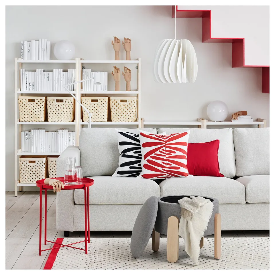Modern living room with a light grey FÖRLUNDA sofa, red accent pillows, side table, and stylish decor.