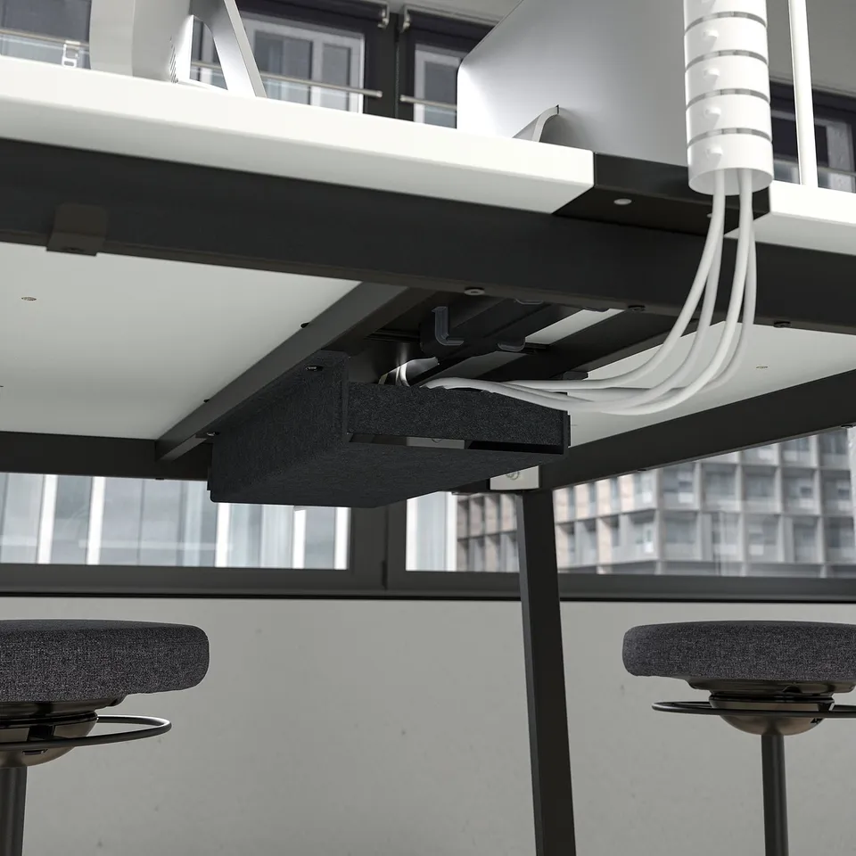 Modern office setup with suspended, adjustable table and chairs, connected by visible cables, suitable for conferences.