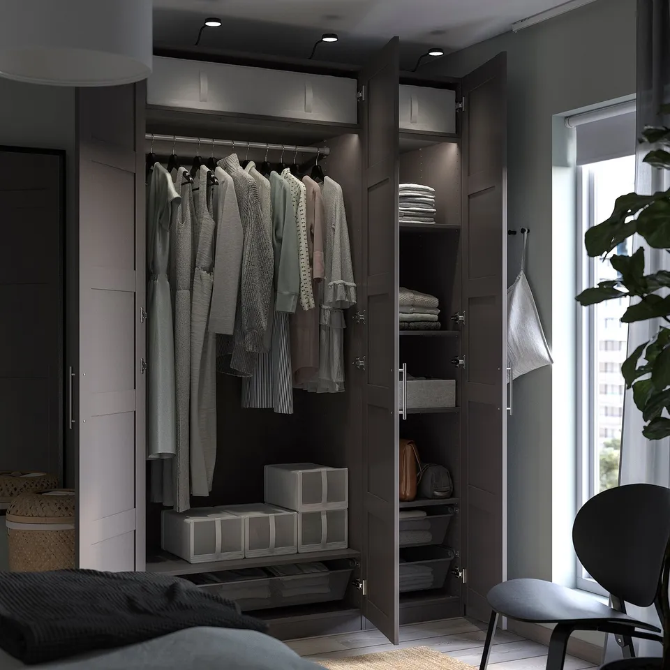 Modern dark brown PAX wardrobe, open to show hangers, folded clothes, and storage boxes.