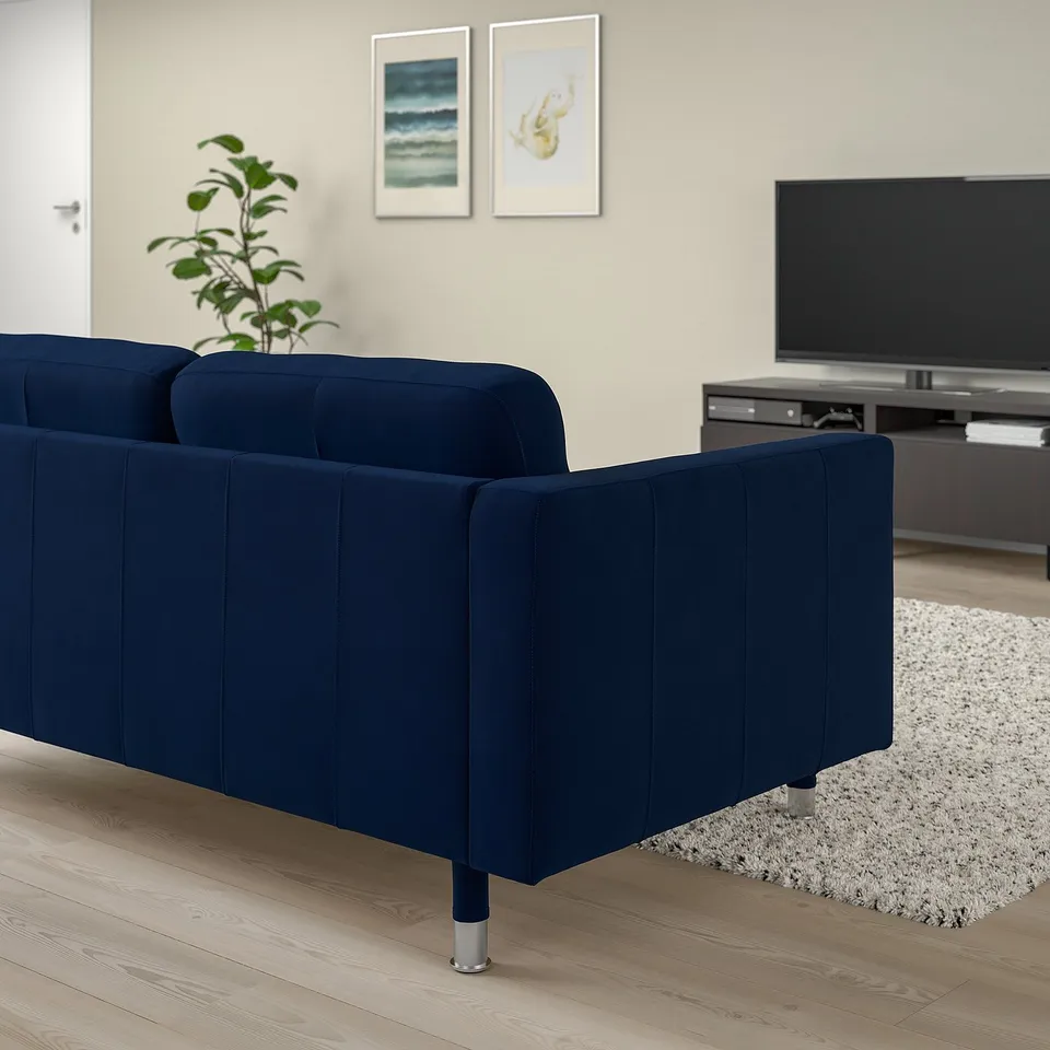 Modern navy blue sofa, elegant design, tall chrome legs, with cushions, fits well in room.