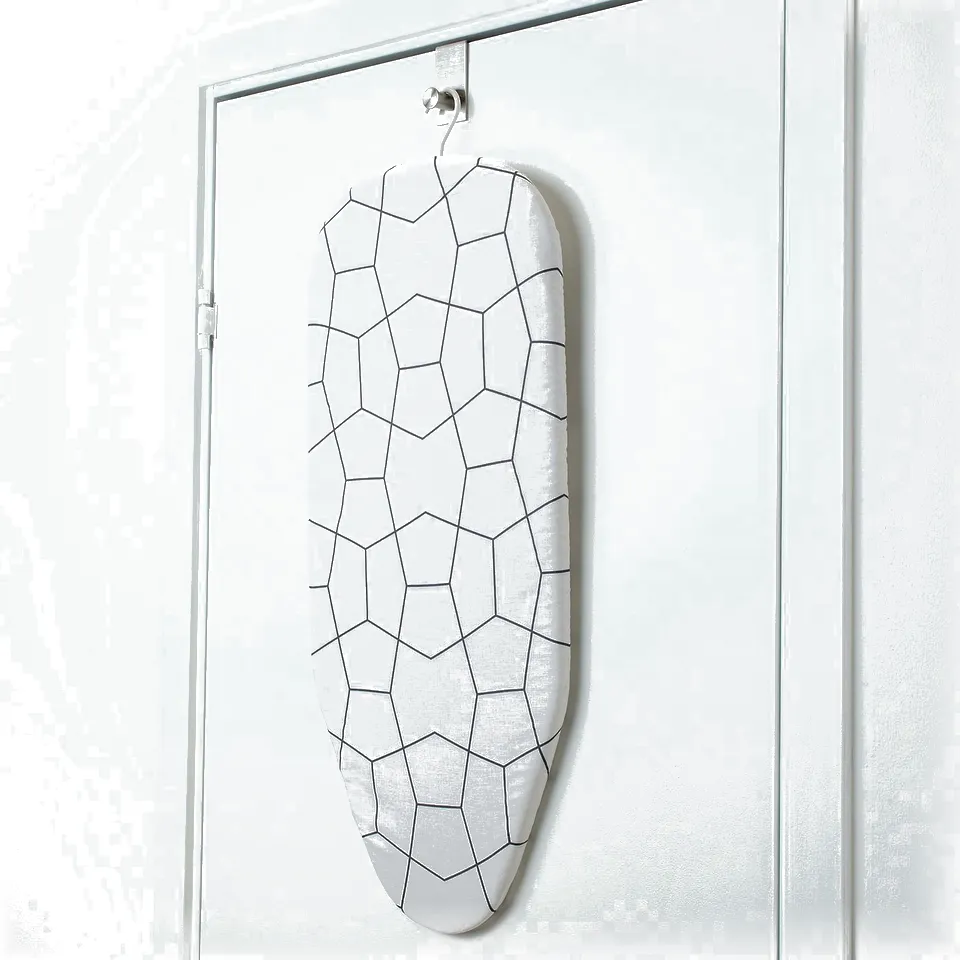 A white ironing board with a geometric pattern hangs on a door hook, flat against a white door.