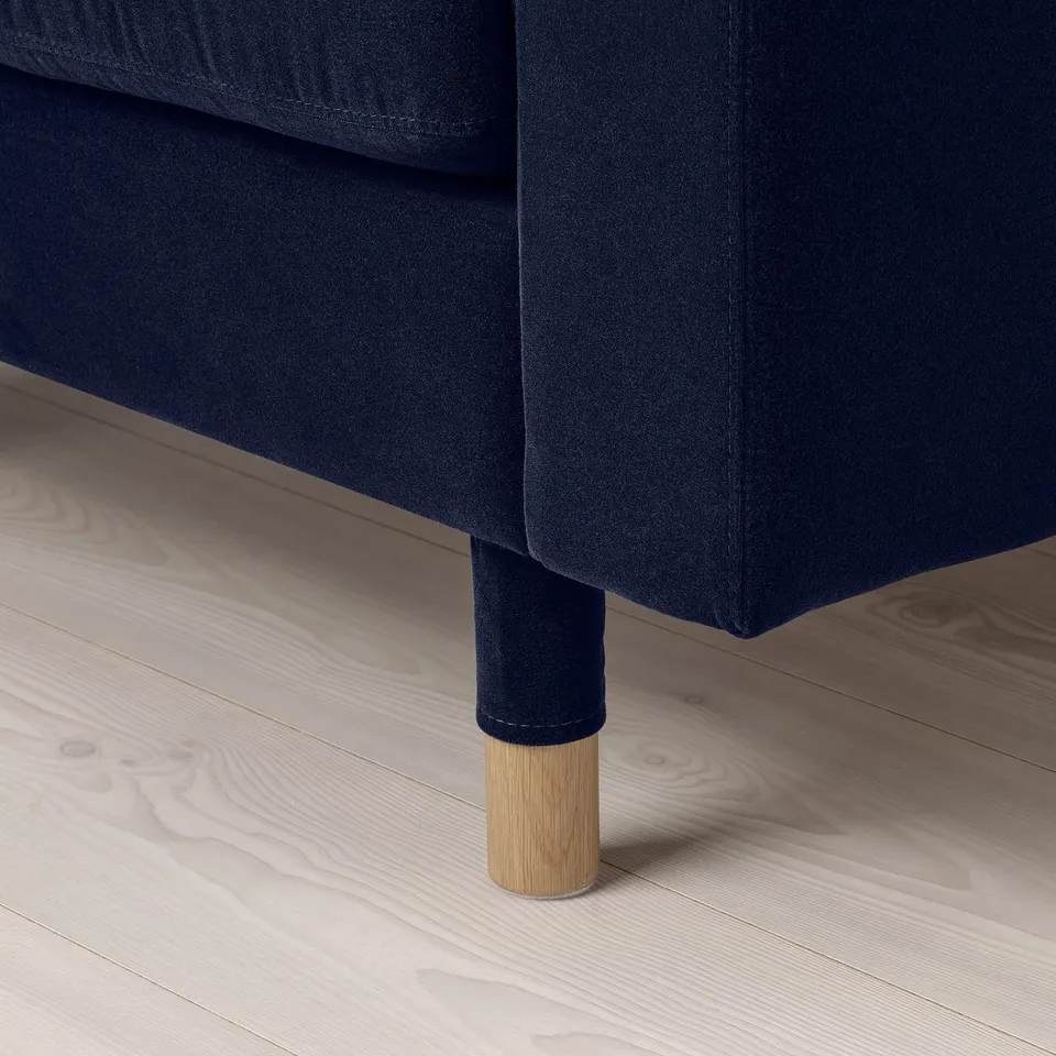 Navy blue sofa with wooden legs; corner view highlighting stitching and fabric quality.