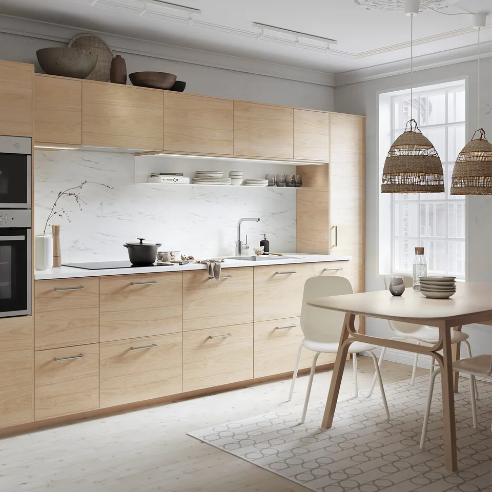 Modern kitchen with light ash cabinetry, marble backsplash, and white dining set.