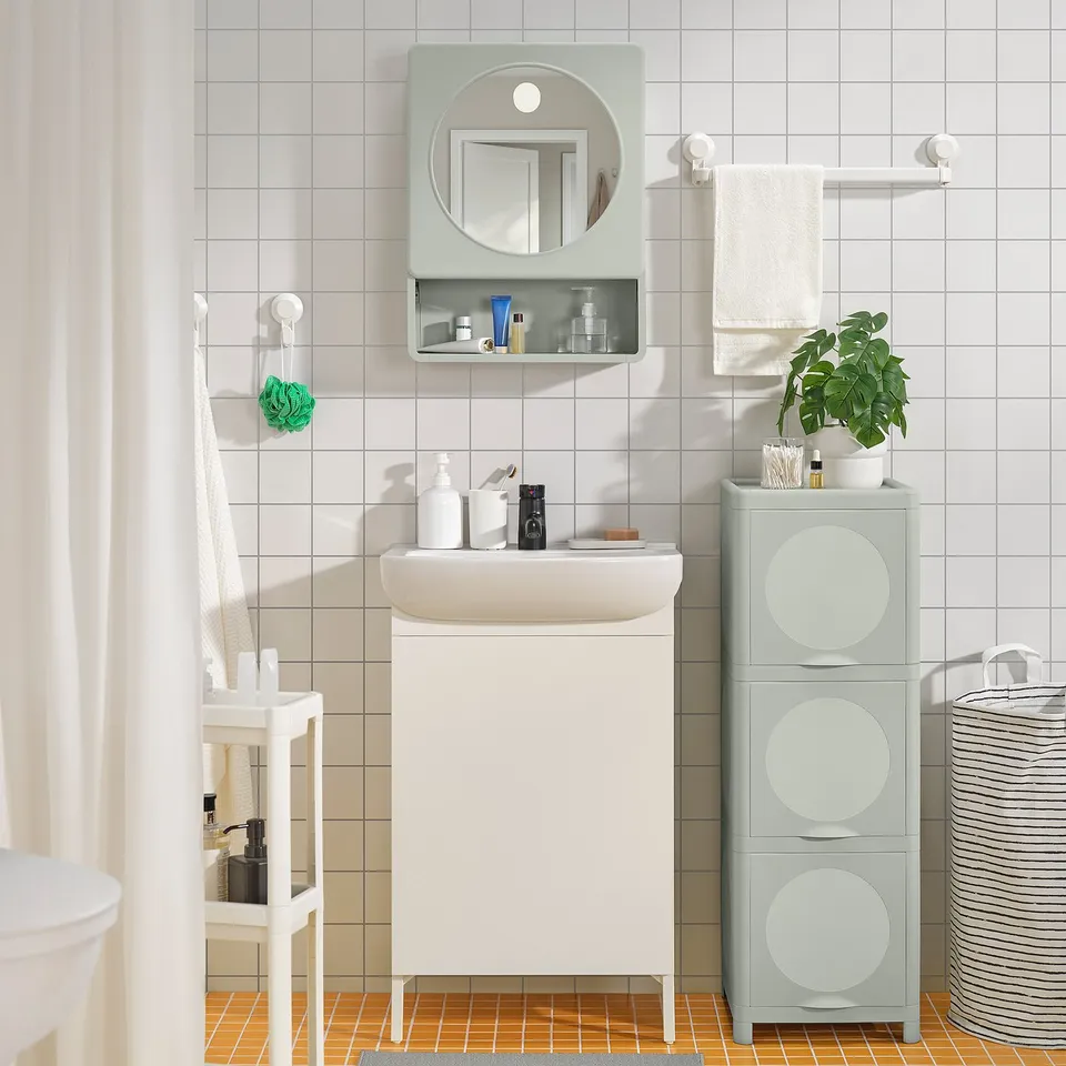 Compact modern bathroom with white IVÖSJÖN cabinet, green accents, mirror, and storage units. Small, sleek, and efficient.