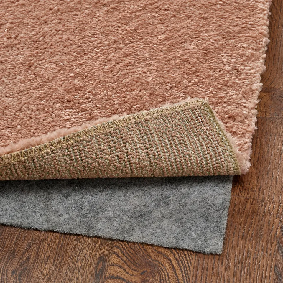 Pink, soft rug shown with non-slip underlay, demonstrating comfort and safety.