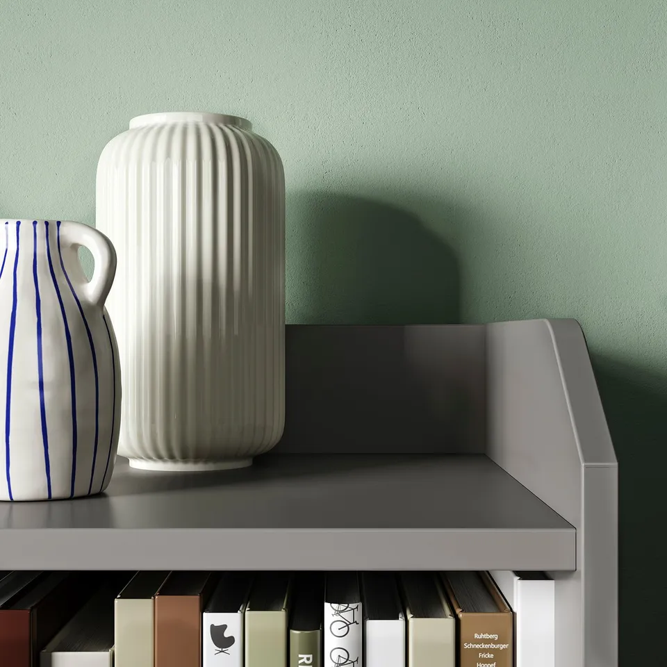 Two vases on a grey shelf against a green wall. One white, the other white with blue stripes.