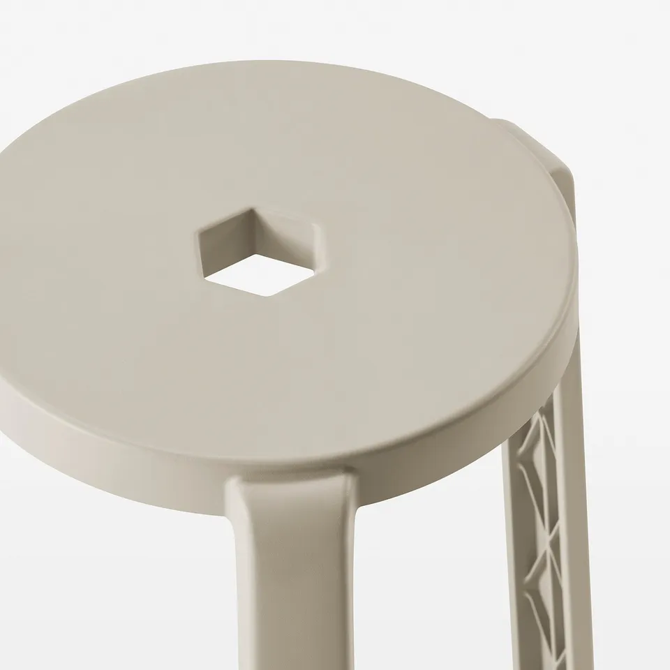Round, beige plastic stool with square cutout on top, three legs with textured pattern.