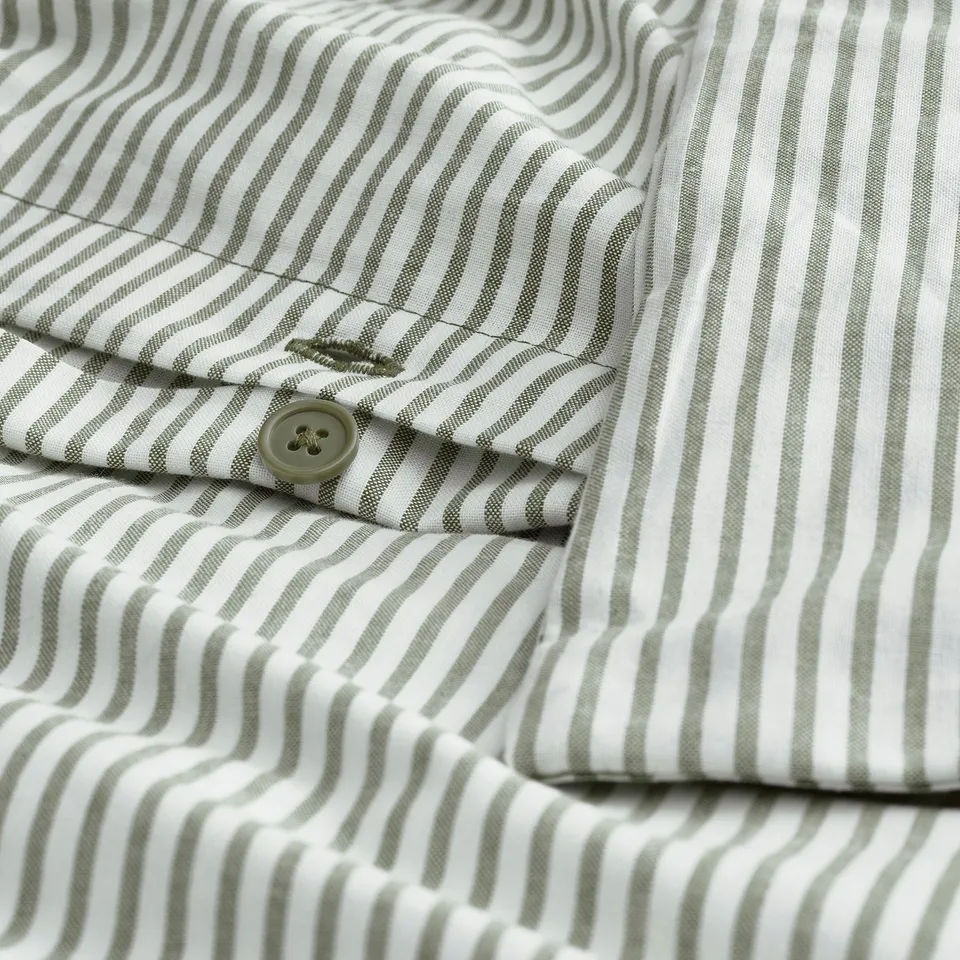 Closeup of green striped fabric with button. Shows texture and pattern, likely SOLFIBBLA.