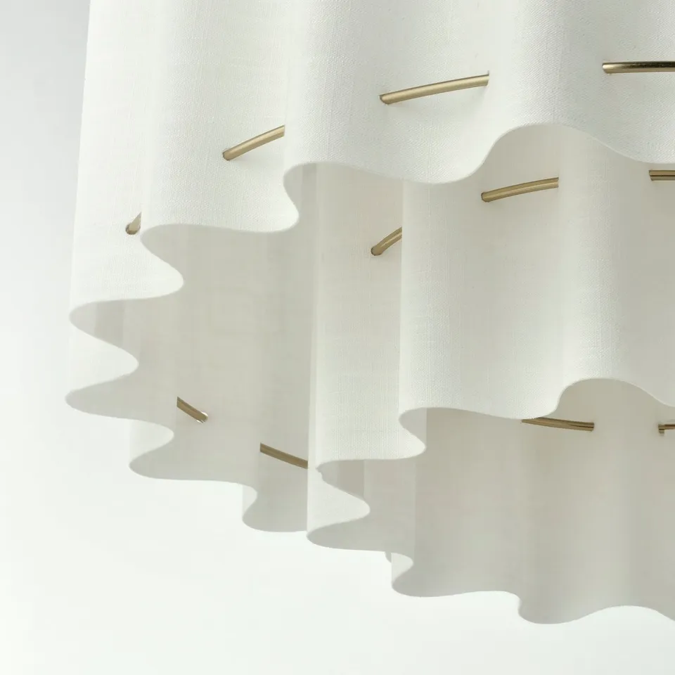 Elegant pendant lamp with wavy textile shade and gold accents, exuding a soft, inviting light.