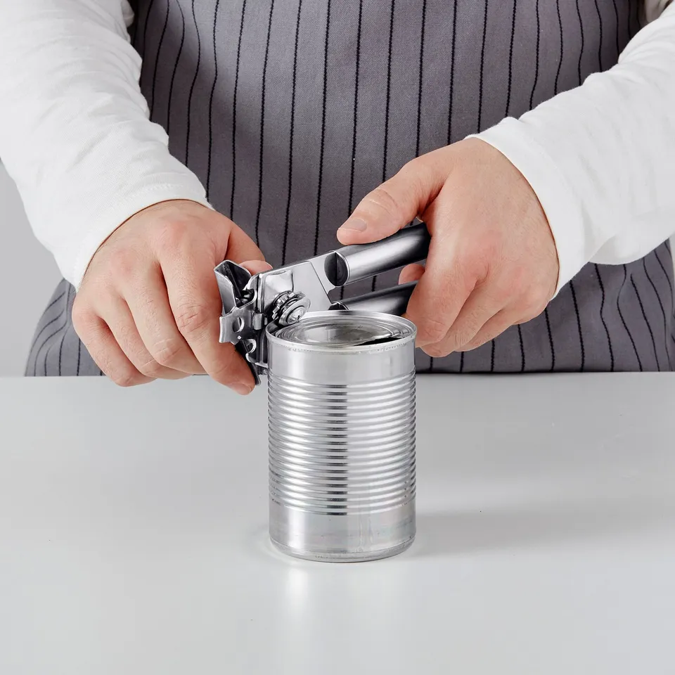 Person using a can opener on a silver metal can.