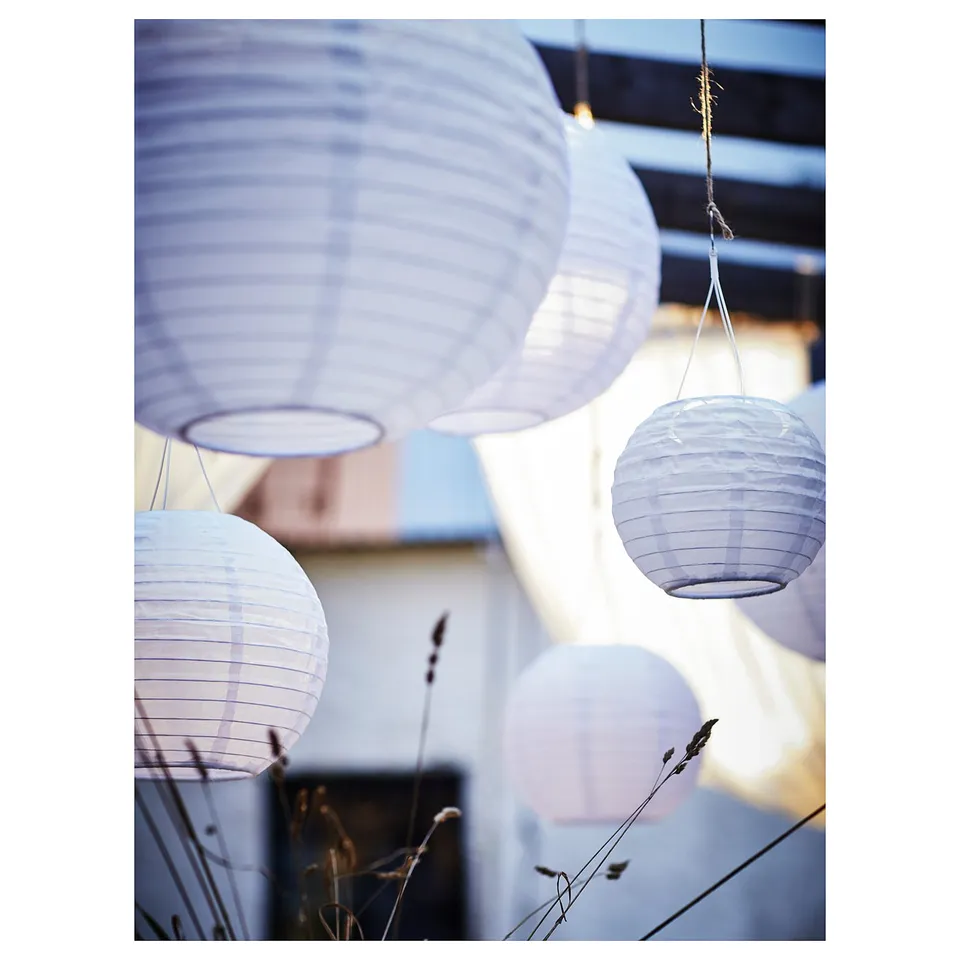 Purple solar lanterns hang outdoor with lighted bulbs.