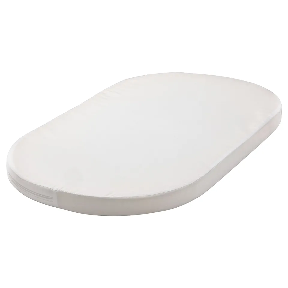 An oval white ÄLSKVÄRD baby mattress with a simple design, made from polyester and cotton materials.